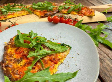 Fertig gebackener High Protein Pizzateig belegt mit Salami, Tomaten, Käse und Rucola